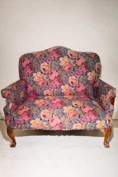 an upholstered floral couch with wooden legs