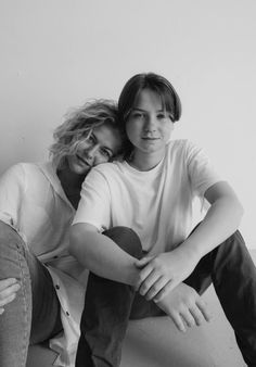 black and white photograph of two people sitting on the floor with their arms around each other