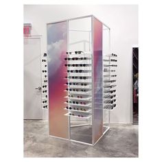 a display case filled with lots of pairs of eyeglasses in front of a white wall