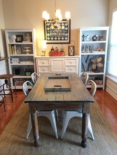 a dining room table and chairs in front of a book shelf with shelves on each side