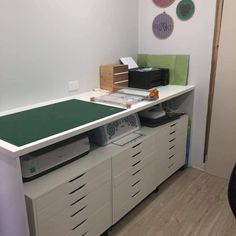 an office desk with drawers, printer and other items on the top shelf in front of it