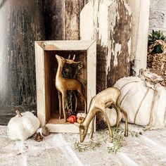 two deer figurines in a wooden box surrounded by pumpkins