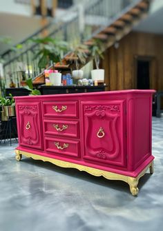 a pink dresser with gold trim and handles in a living room or dining room area