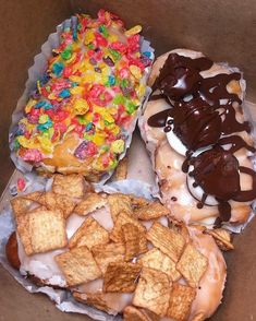 three different types of doughnuts in a box with chocolate, candy and cheetos