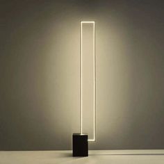 a black and white floor lamp with a square light in the middle on top of it