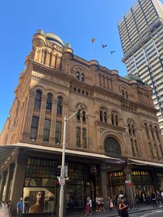 an old building with many windows and people crossing the street in front on a sunny day