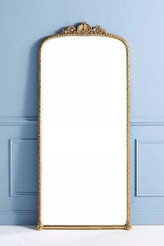 an ornate gold framed mirror against a blue wall