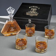 four whiskey glasses sitting next to an empty bottle