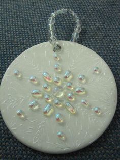 a white ornament hanging from a chain on a blue carpeted surface with beads