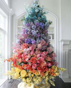 a vase filled with lots of flowers on top of a wooden table next to a window