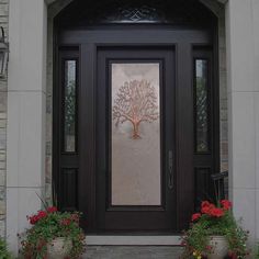 the front door is decorated with red flowers and a decorative tree on it's glass panel