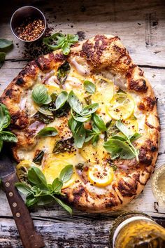 a pizza sitting on top of a wooden table covered in green leaves and lemon slices