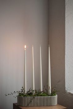 white candles are arranged in a vase on a table