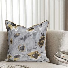 a white couch with a gray and gold pillow on it