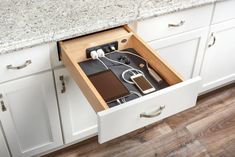 an open drawer in the middle of a kitchen counter with cords and wires inside it