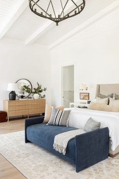 a large bed sitting in the middle of a bedroom next to a dresser and lamp