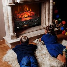 two children sitting on the floor in front of a fireplace with an open fire place