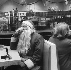 two people sitting at a table in a restaurant, one with long hair and the other wearing a santa claus hat