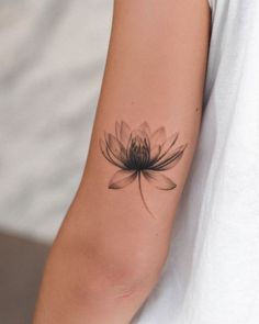 a woman's arm with a black and white flower tattoo on her left arm