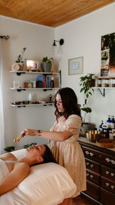 a woman is getting her hair done by another woman in a room with wooden floors