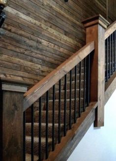 a wooden staircase with wrought iron handrails and wood paneling on the wall