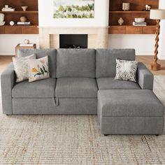 a living room with a large gray sectional couch and pillows on the bottom right hand corner