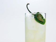 a tall glass filled with ice and a green pepper