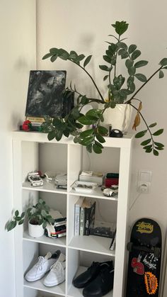 a white book shelf filled with shoes and plants