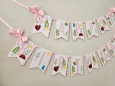 a pink banner with ladybugs and flowers hanging from it's sides on a wall