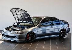 a silver car with its hood open on the floor