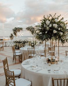 the tables are set with white linens and gold chairs for an elegant wedding reception