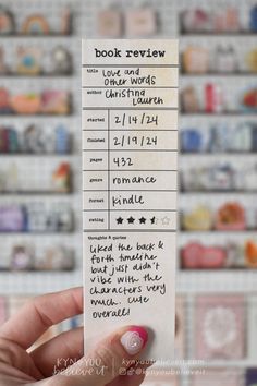 a person holding up a book review card in front of a wall of bookshelves