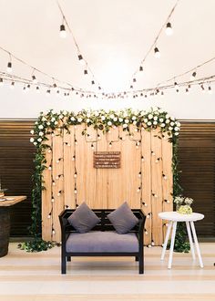 a room decorated with lights and flowers on the wall, two couches in front of a wooden screen