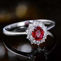 a close up of a ring with a red stone in it on a black surface