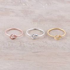 three different rings sitting on top of a wooden table with one ring in the middle