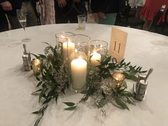 a table with candles and greenery on it