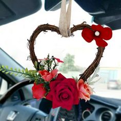 a heart shaped wreath with flowers hanging from it's side in the front seat of a car