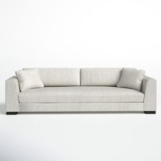 a white couch sitting on top of a hard wood floor next to a gray wall