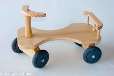 a wooden toy car sitting on top of a white table next to a blue wheel