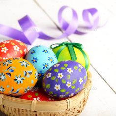 colorful easter eggs in a basket with purple ribbon and bow on white wooden background - stock photo - images