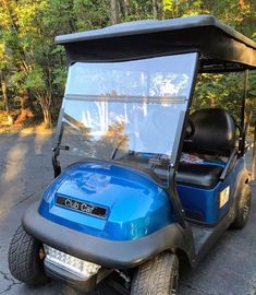 a blue golf cart is parked on the side of the road in front of some trees