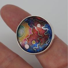 a person's hand holding a ring with an image of the planets in it