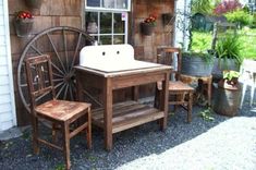 an old fashioned sink sitting on top of a wooden table next to two chairs and a wheel