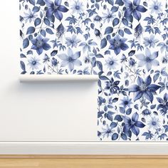 a wall with blue flowers on it next to a wooden floor and white wallpaper