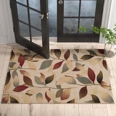 a door mat with leaves on it in front of a glass door and potted plant