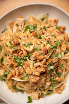 a white plate topped with lots of food on top of a wooden table next to a fork