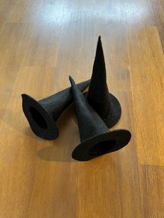 three black cones sitting on top of a wooden floor