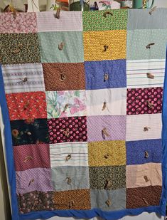 a quilt is hanging on the wall in front of a window with birds and flowers