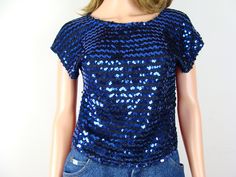 Fabulous and flashy vintage sequin and metallic glitter top from the late 70s / early 80s.  Features a wide rounded neckline with a straight cropped silhouette and armhole openings that look like a short cap sleeve when worn.  Made of a black knit material with metallic blue glitter lurex threads throughout and rows of blue sequins sewn on the front.  Freshly laundered and ready to wear. Label: No label present. Fiber Content: No label present, but seems to be a knit polyester with lurex. Stampe Y2k Plus Size, Vintage Sequin Top, Textured Knit Cardigan, Coogi Sweater, Disco Glam, Glitter Shirt, Glitter Top, 80s Party, Pink Boots