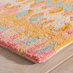 a multicolored area rug on a wooden floor with a wood floor in the background